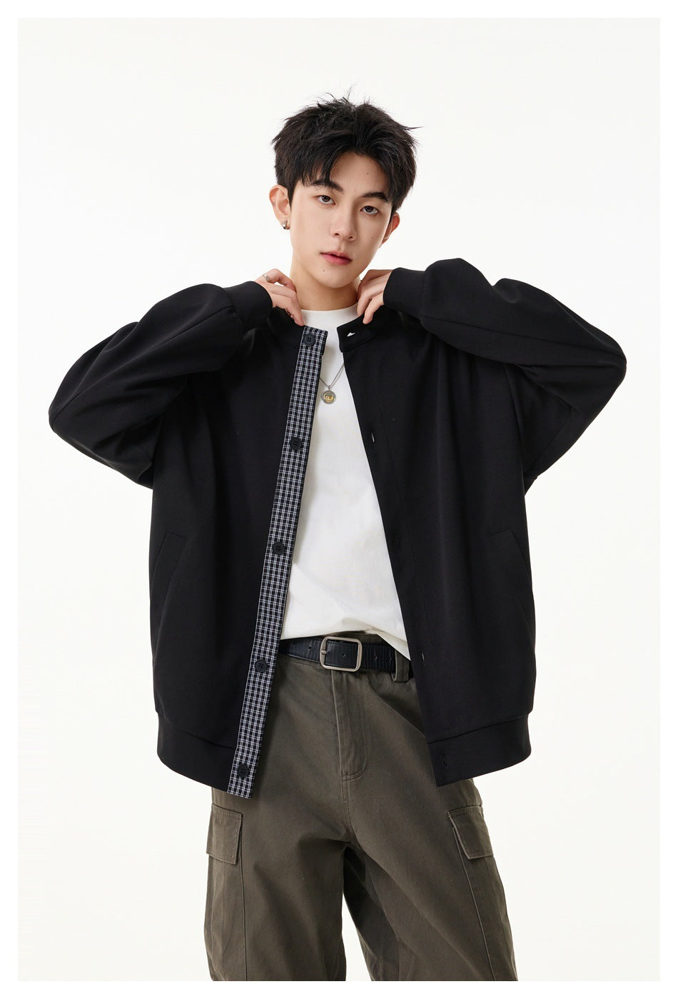Model holds open a black stand-collar jacket, showing its checked placket, white shirt, and side pockets.