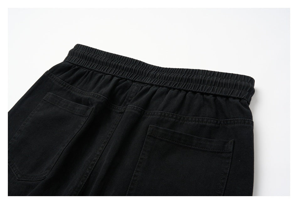 Cropped rear view of black trousers with an elastic waistband and two back pockets.