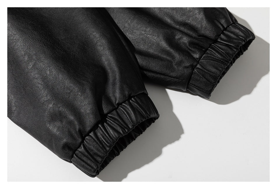 Close-up of two gathered elastic cuffs on a black leather-look garment.