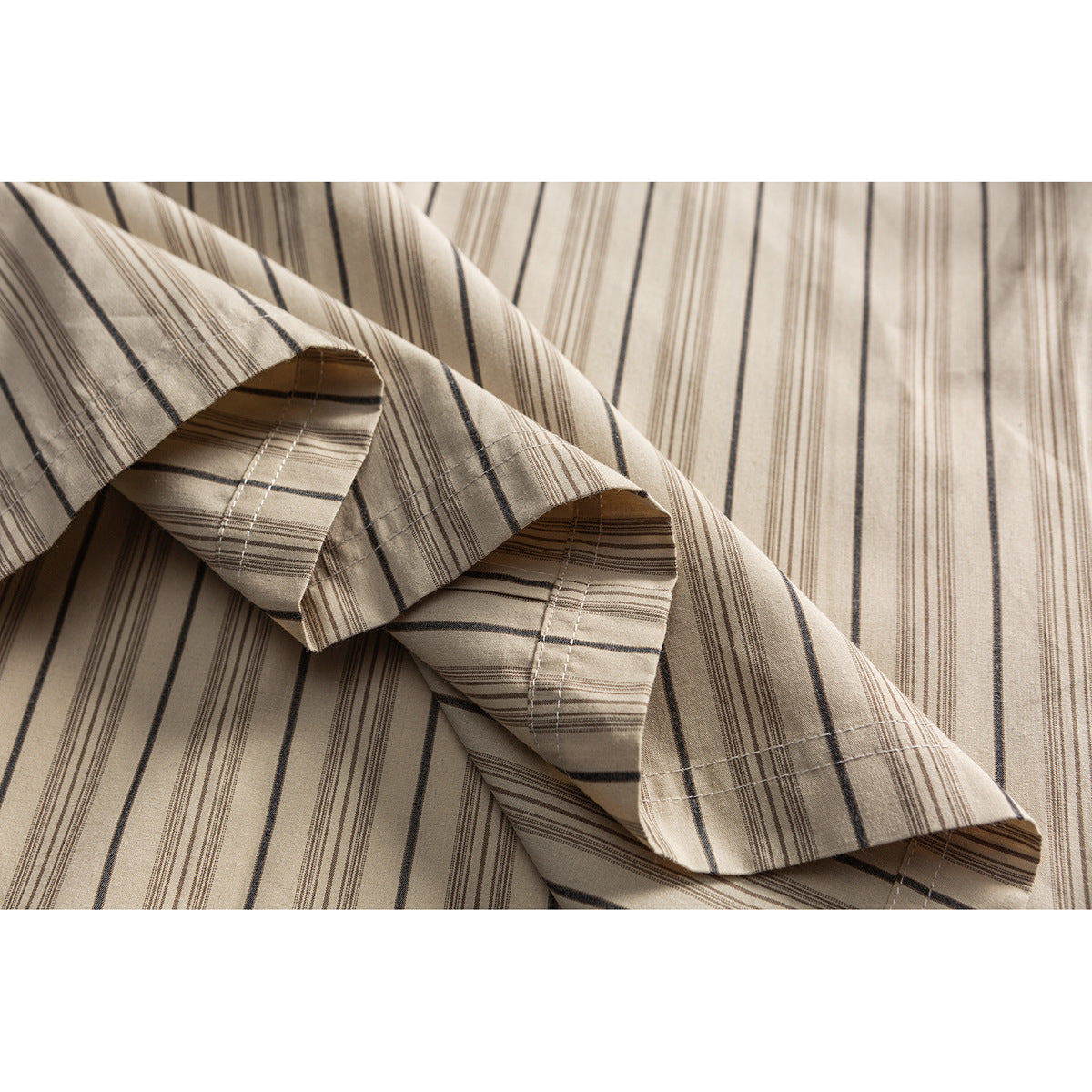 Close-up of the beige shirt's striped short sleeve and stitched cuff against its matching body fabric.