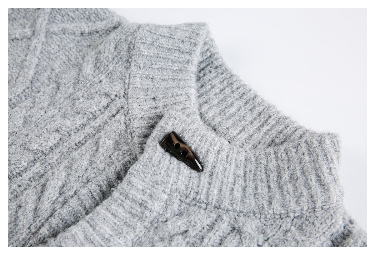 Close-up of a light gray cable-knit sweater's ribbed collar and dark toggle button.