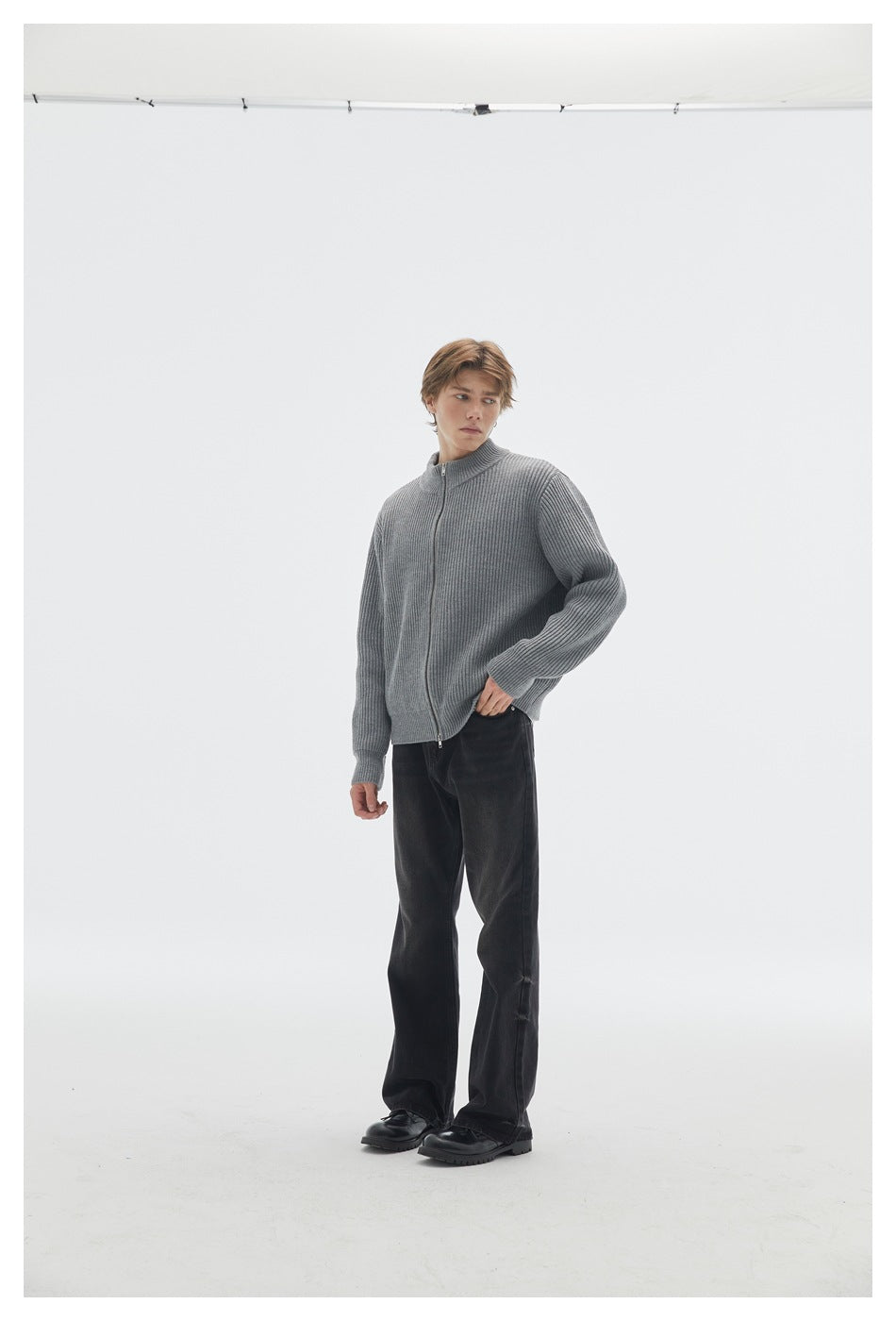 Full-length model wearing a zipped gray ribbed cardigan with black trousers and chunky black shoes.