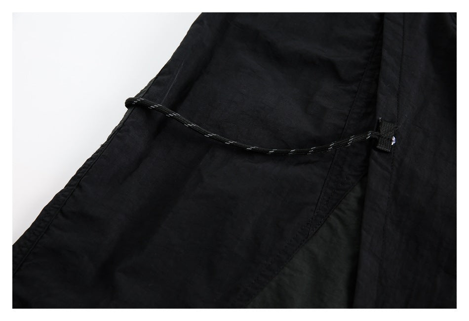 Close-up of black garment fabric with a curved cord and stitched panels.