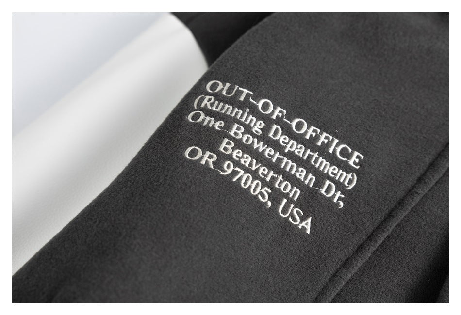 Close-up of a dark jacket with white embroidered English text on the fabric.
