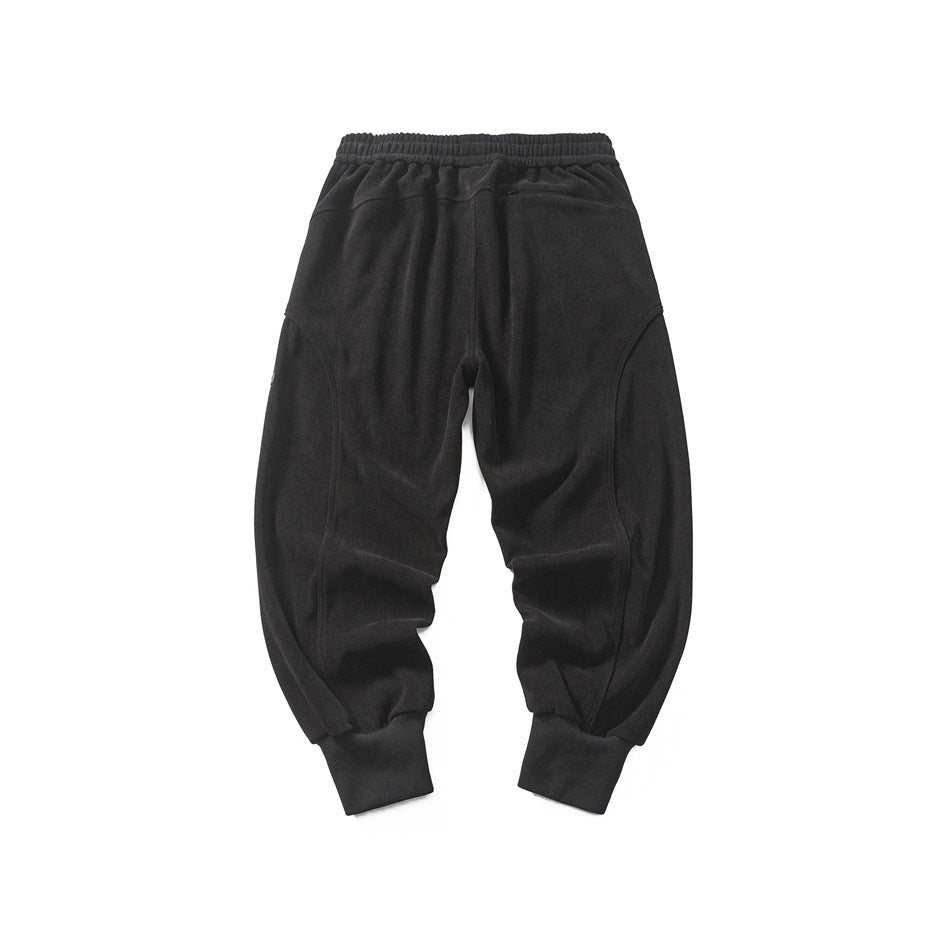 Back view of black jogger pants with elastic waistband, curved leg seams and ribbed cuffs