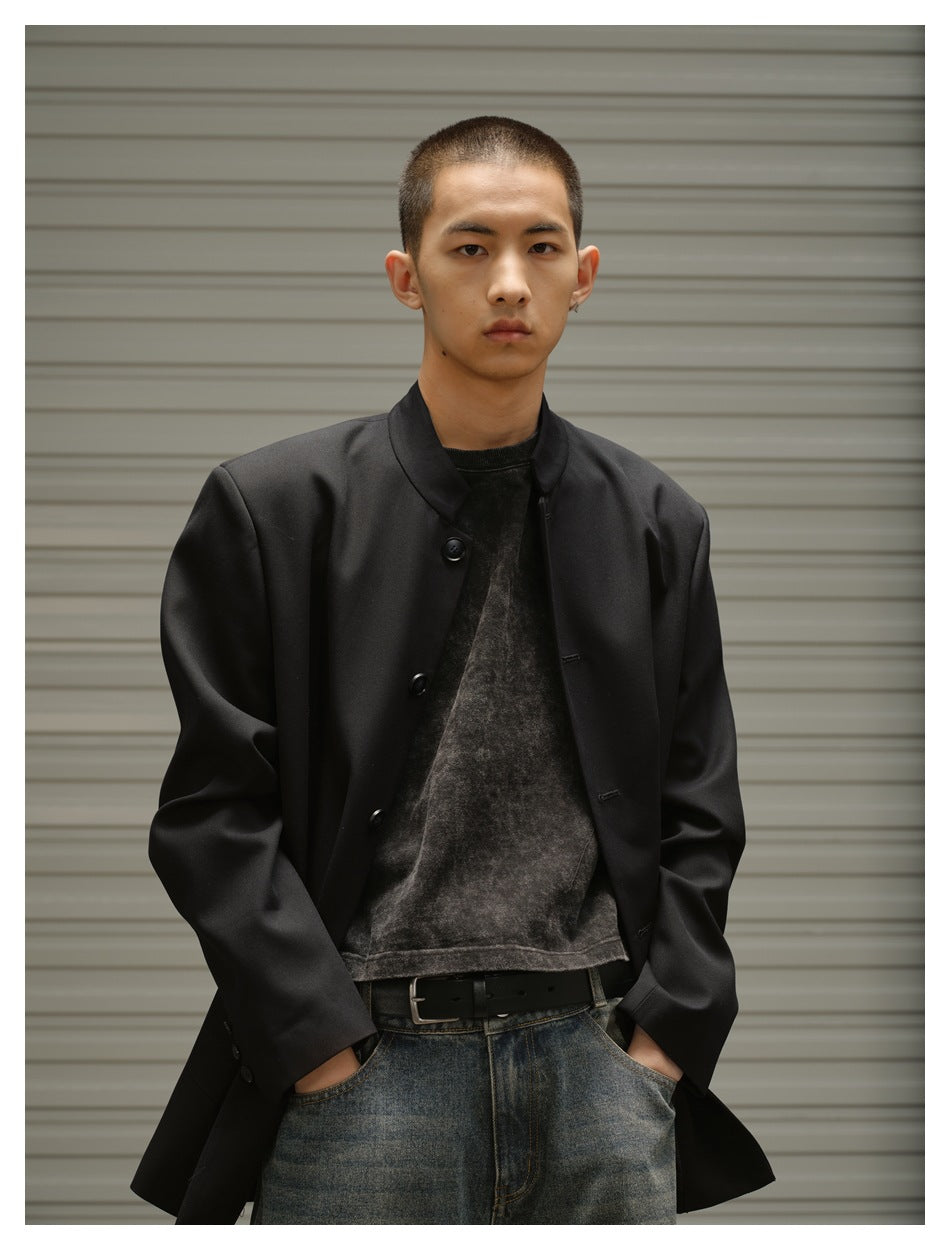 Close front view of a model wearing a black button-front stand-collar jacket over a dark shirt.