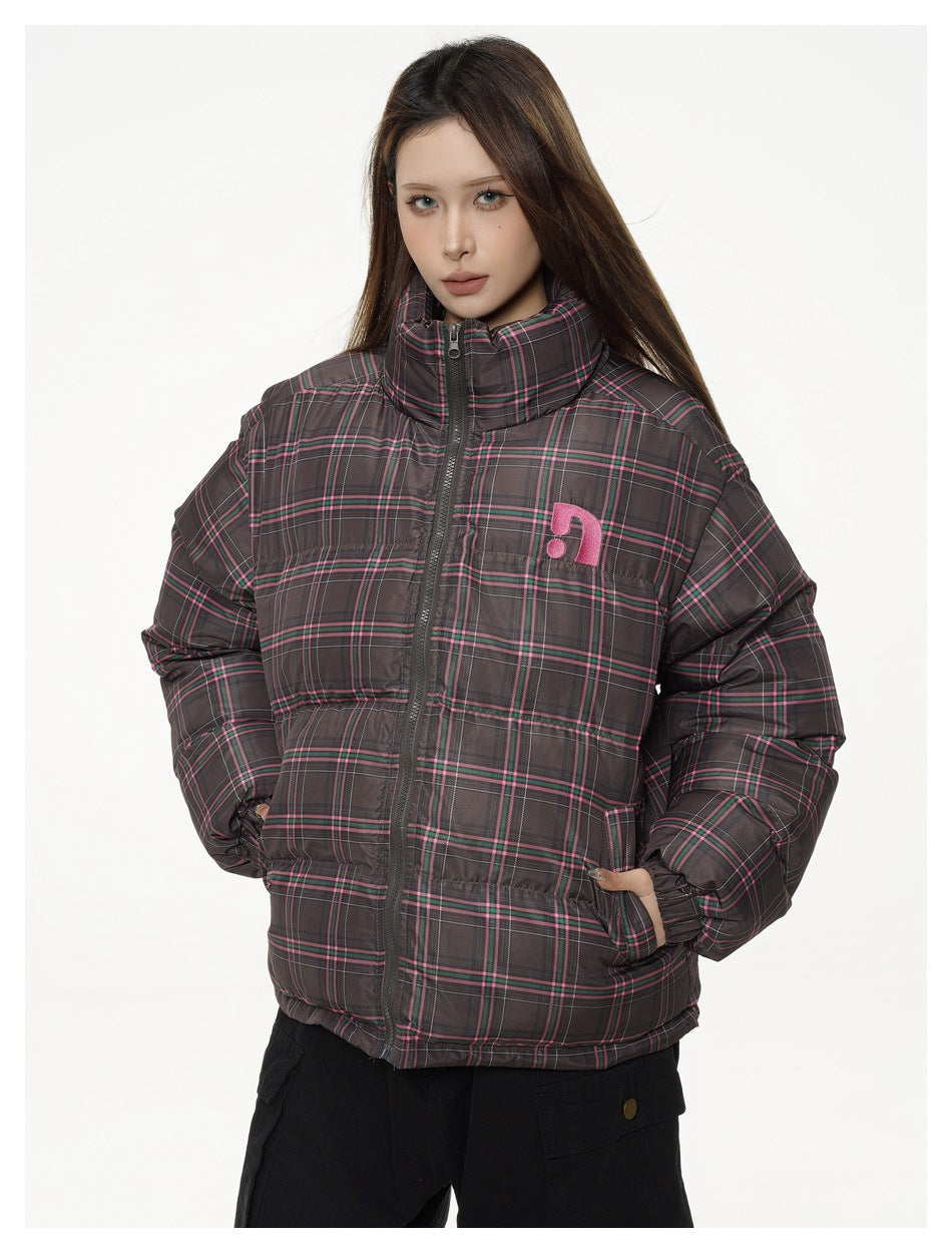 Woman wearing a brown plaid puffer jacket with pink and green stripes, zipped stand collar, hands in pockets