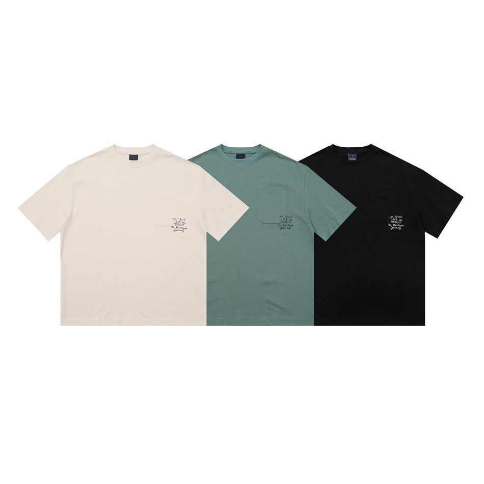 Front views of three short-sleeve crew-neck T-shirts in cream, sage green, and black, each with a chest pocket and small