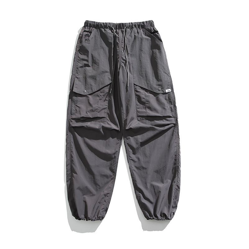 Gray cargo pants flat lay with elastic drawstring waist, large flap pockets and gathered ankle hems