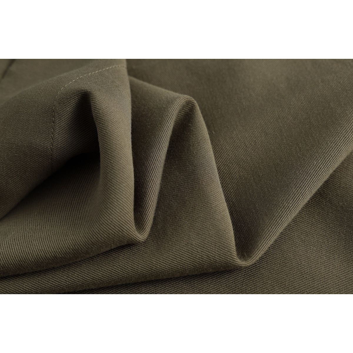 Macro view of olive-brown trouser fabric folded to show its surface and diagonal weave.