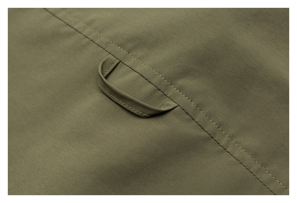 Close-up of an olive garment showing a small fabric loop and diagonal double stitching.
