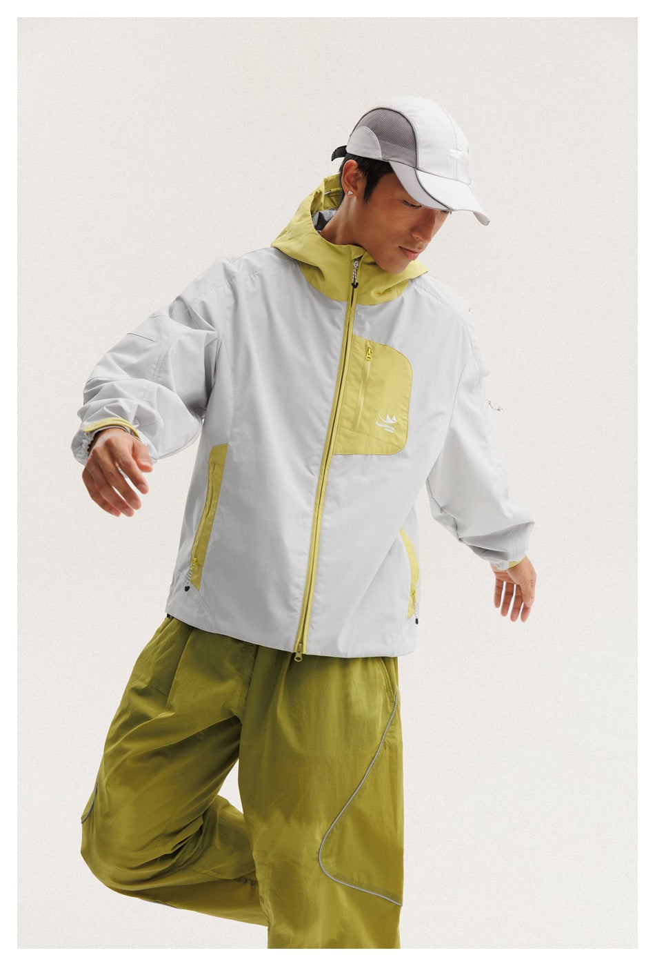 Closer view of a model wearing a light gray jacket with a yellow-green hood, chest pocket and trim.