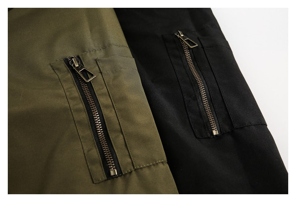 Close-up of olive and black jacket panels, each with a vertical zip pocket.