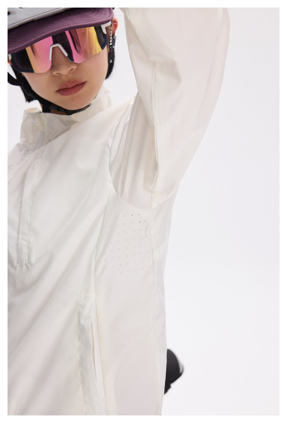 Close-up of a white jacket's underarm ventilation perforations and seam.