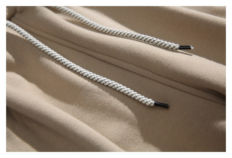 Close-up of beige pants with white drawstrings woven in dark diagonal stripes and black tips.