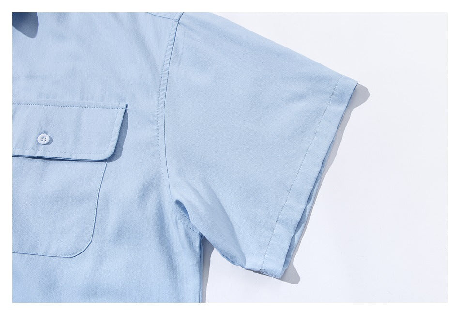 Close-up of a light blue short sleeve and part of a buttoned flap chest pocket.