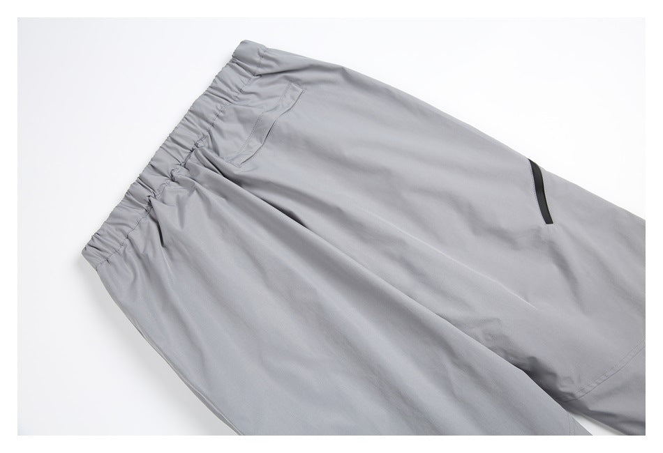 Angled flat lay of gray pants showing the elastic waistband, front pocket, and black trim detail.