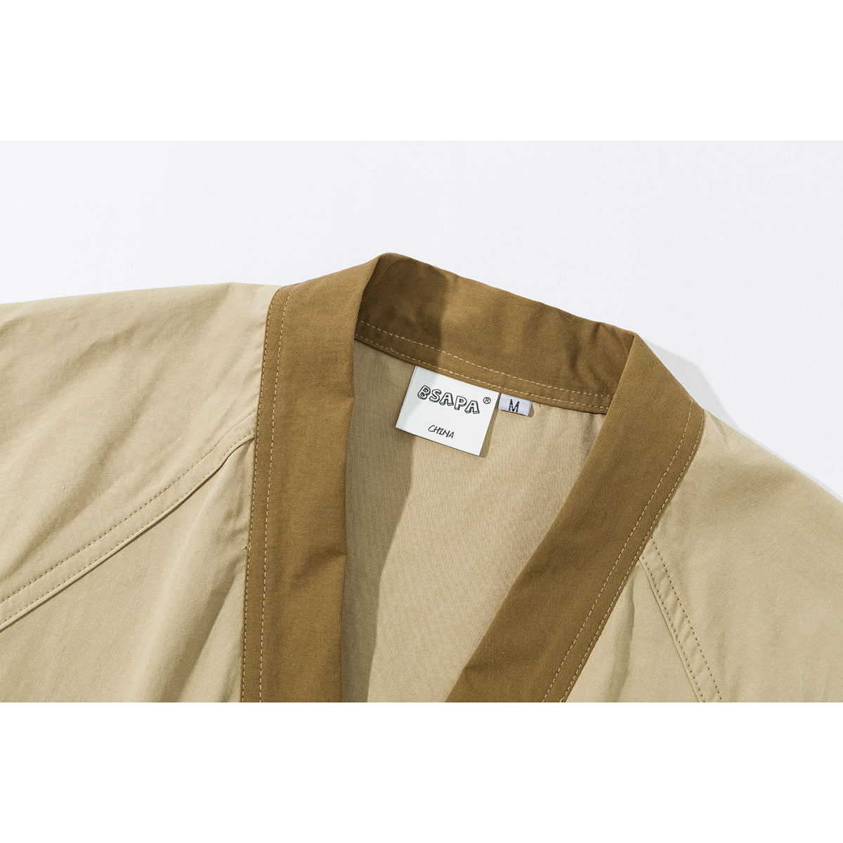 Close-up of a beige jacket with a brown shawl-style collar and a visible neck label.
