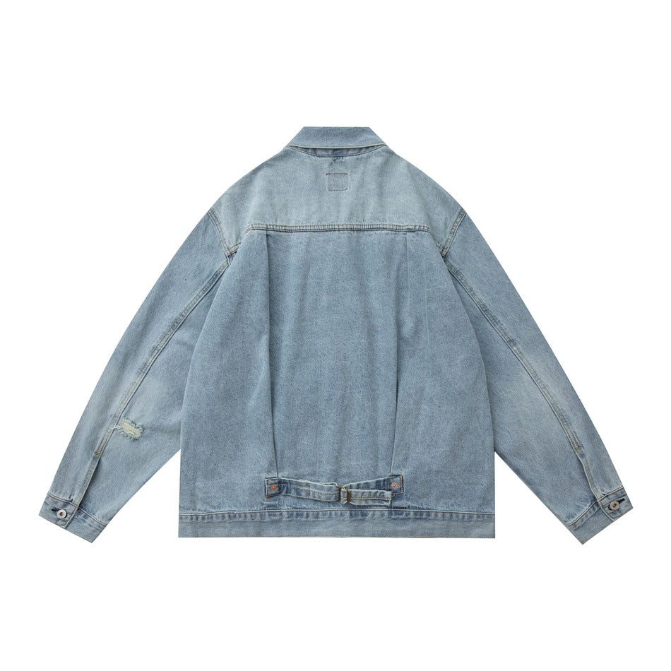 Back view of light-blue washed denim jacket with yoke, back pleat, buckle strap at the hem and buttoned cuffs