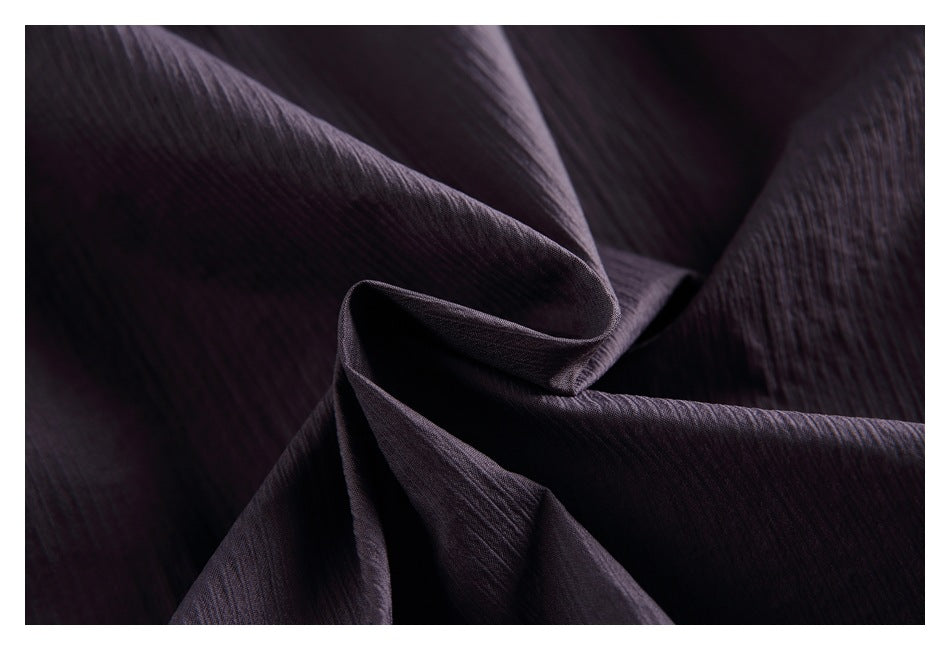Close-up of dark plum fabric gathered to show its fine crinkled texture.