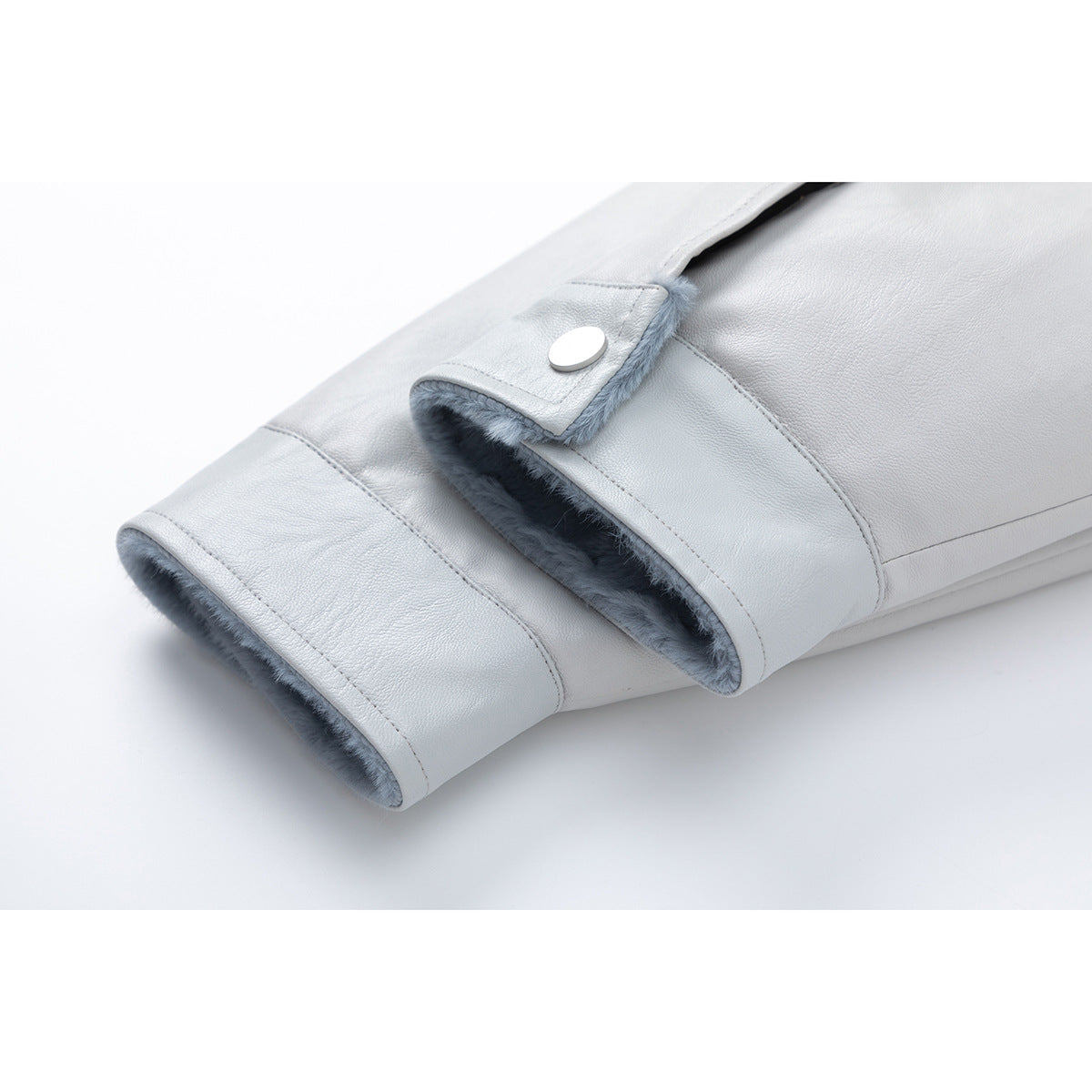 Close-up of a pale gray jacket sleeve cuff with blue fuzzy lining and a snap tab.