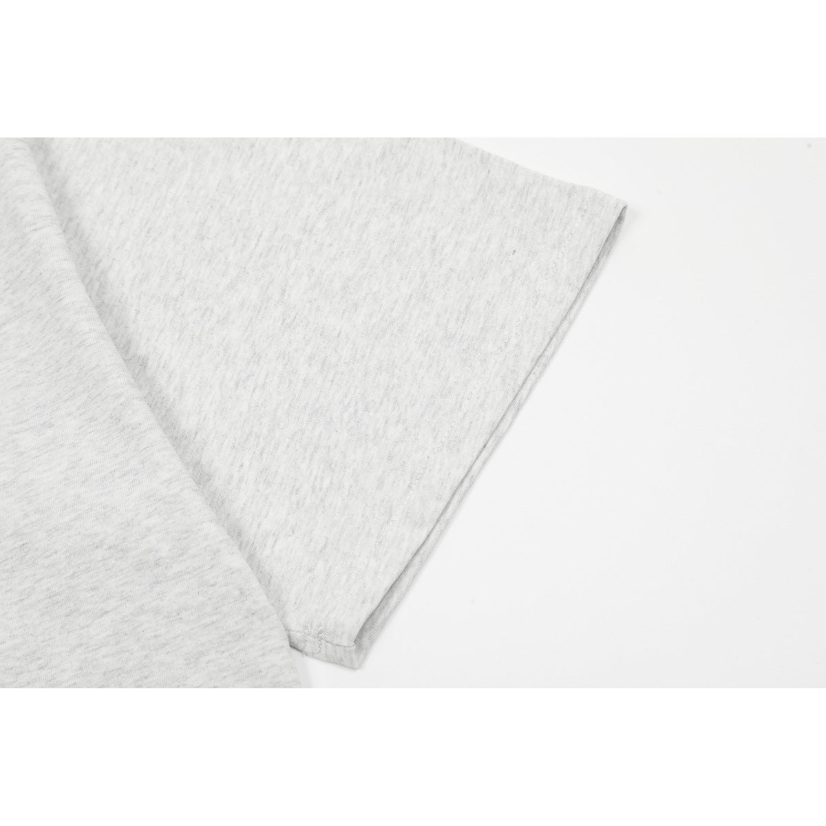 Close-up of a light gray heather T-shirt sleeve and its stitched edge.