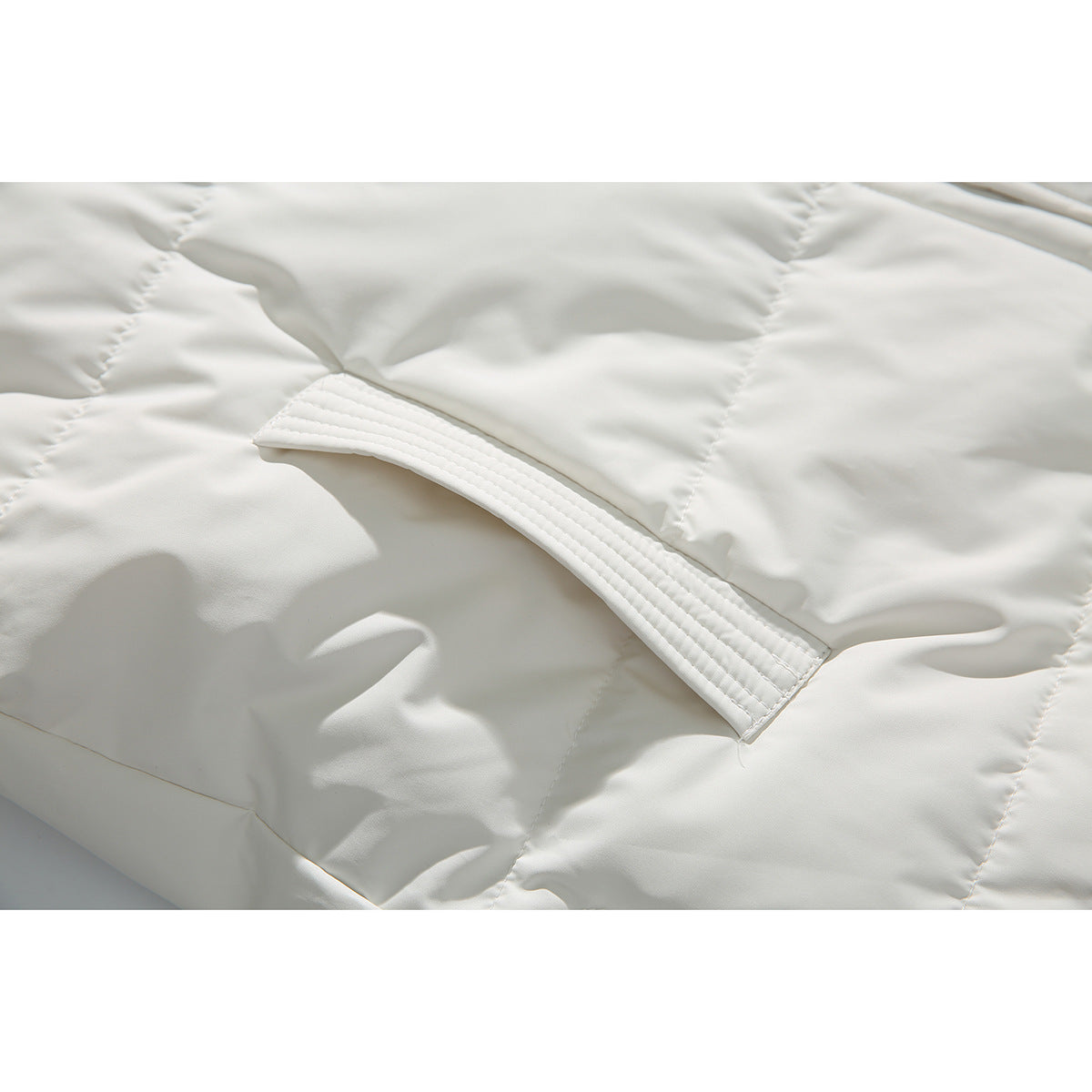 Close-up of ivory quilted coat fabric and a stitched pocket opening.