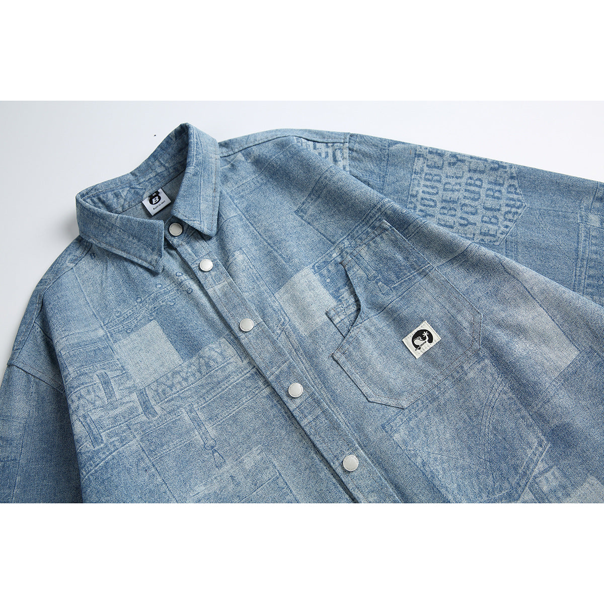 Close-up of a light blue patterned button-up shirt, showing its pointed collar, snap buttons, and chest pocket.