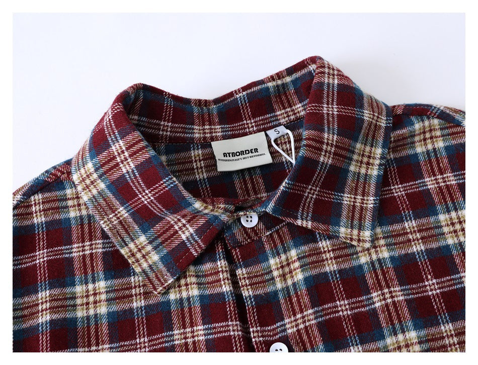 Close-up of the collar, buttons and sewn-in neck label on a burgundy, navy, cream and tan plaid shirt.