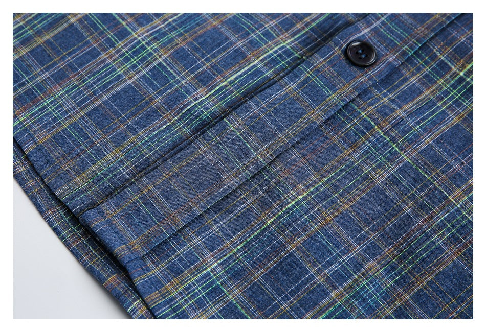 Close-up of a dark button and stitched placket on a blue shirt with multicolored plaid checks.