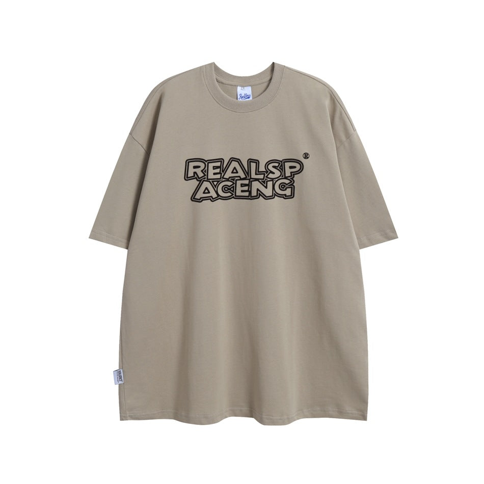 Taupe oversized crew-neck T-shirt with short sleeves and black outlined lettering on the chest, shown from the front.