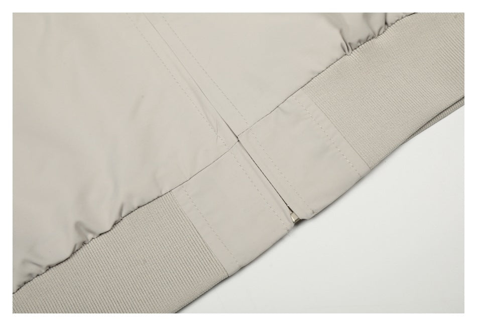 Close-up of the ivory jacket hem with ribbed knit trim and a small metal zipper pull.