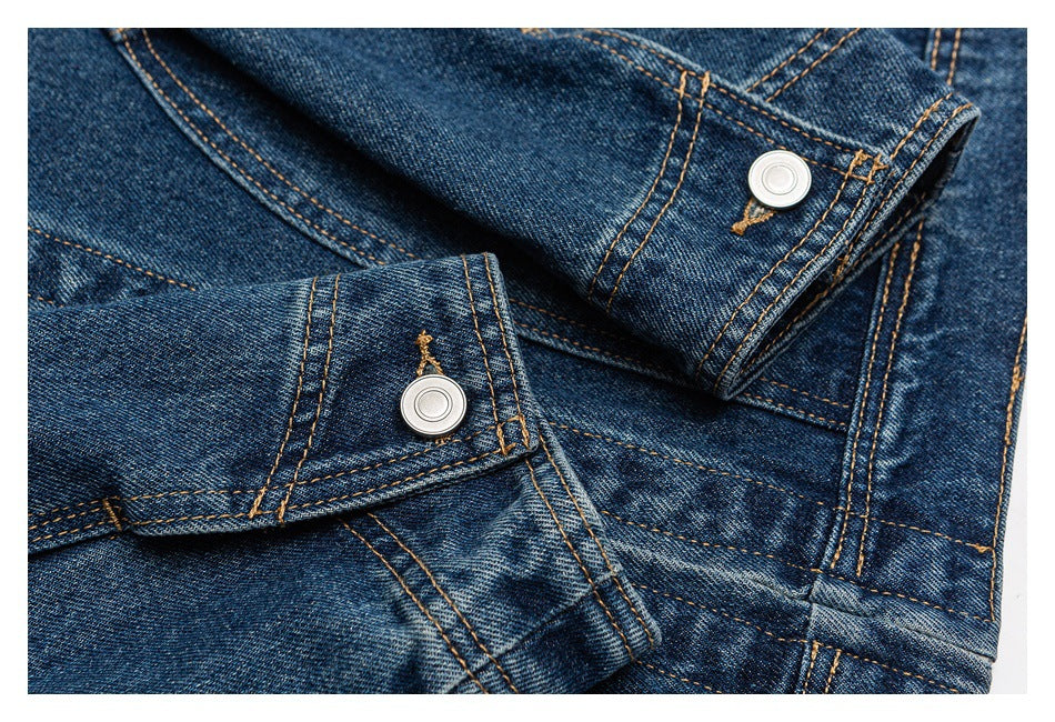 Close-up of blue denim jacket cuffs with silver snap buttons and tan stitching.