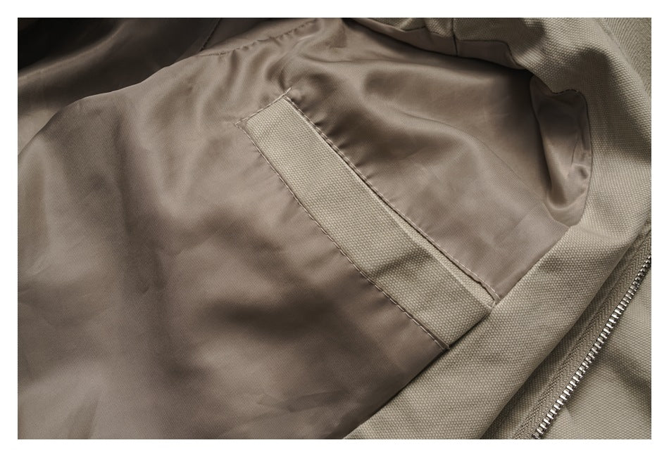 Close-up of a taupe jacket interior with smooth lining, a stitched textured strip, and a metal zipper.