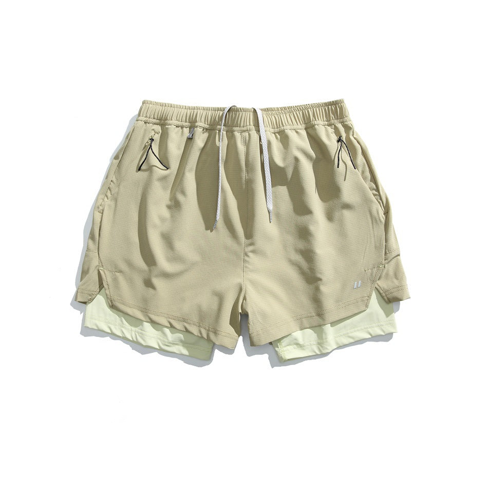 Light khaki double-layer athletic shorts with pale green inner layer, drawcord and zip pockets, flat lay