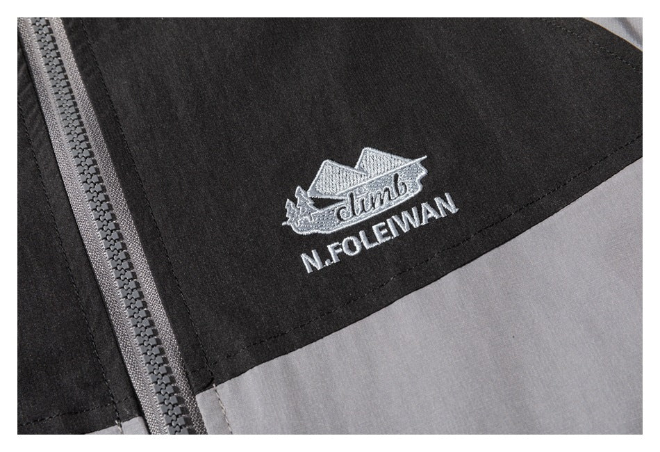 Close-up of embroidered lettering and emblem on a black jacket panel beside the zipper.