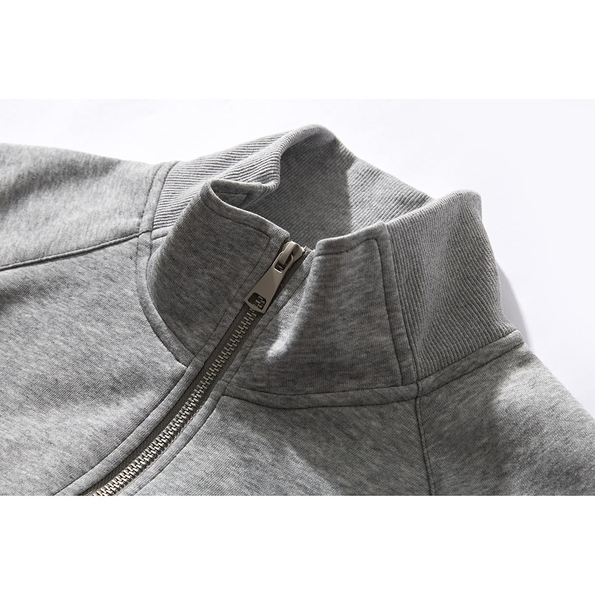 Close-up of a gray jacket's ribbed stand collar and metal front zipper.