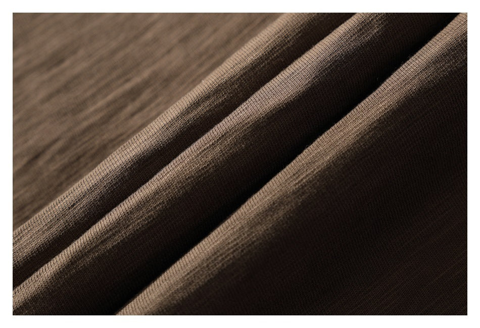 Close-up of brown knit fabric arranged in folds, showing its fine textured surface.