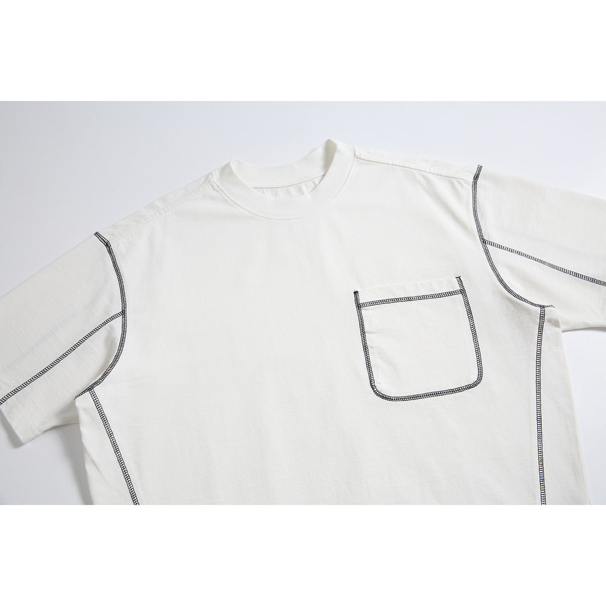 Close-up of an off-white short-sleeve T-shirt showing its crew neck, chest pocket, and dark contrast stitching.