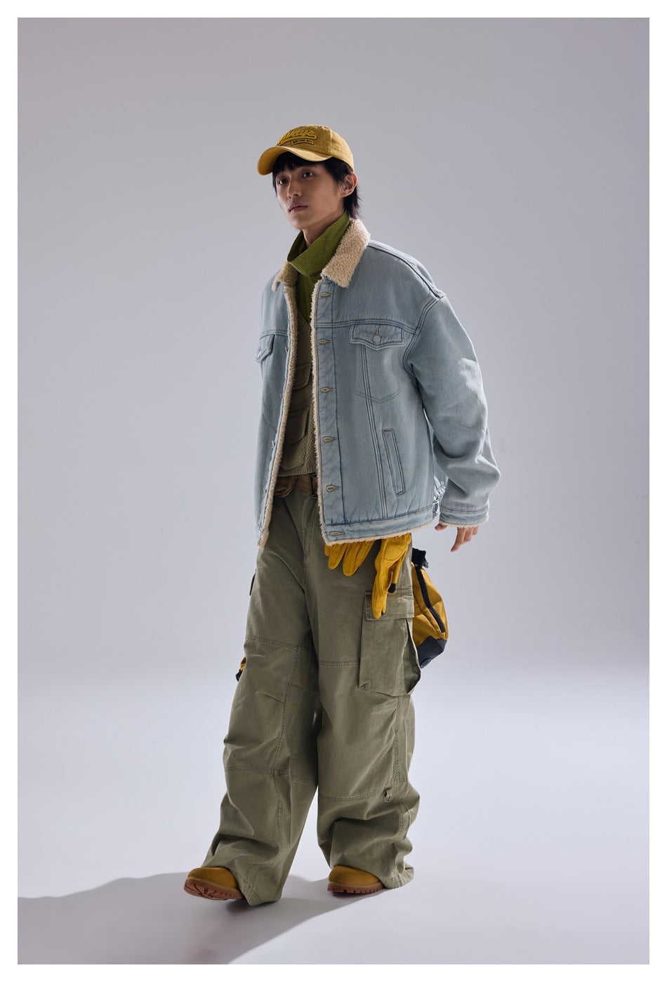 Three-quarter view of a model wearing a light blue sherpa-collar denim jacket and olive cargo pants.