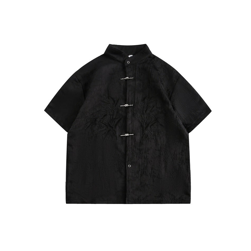 Black short-sleeve stand-collar shirt with metal knot fastenings and tonal embroidered bamboo leaves, flat front view