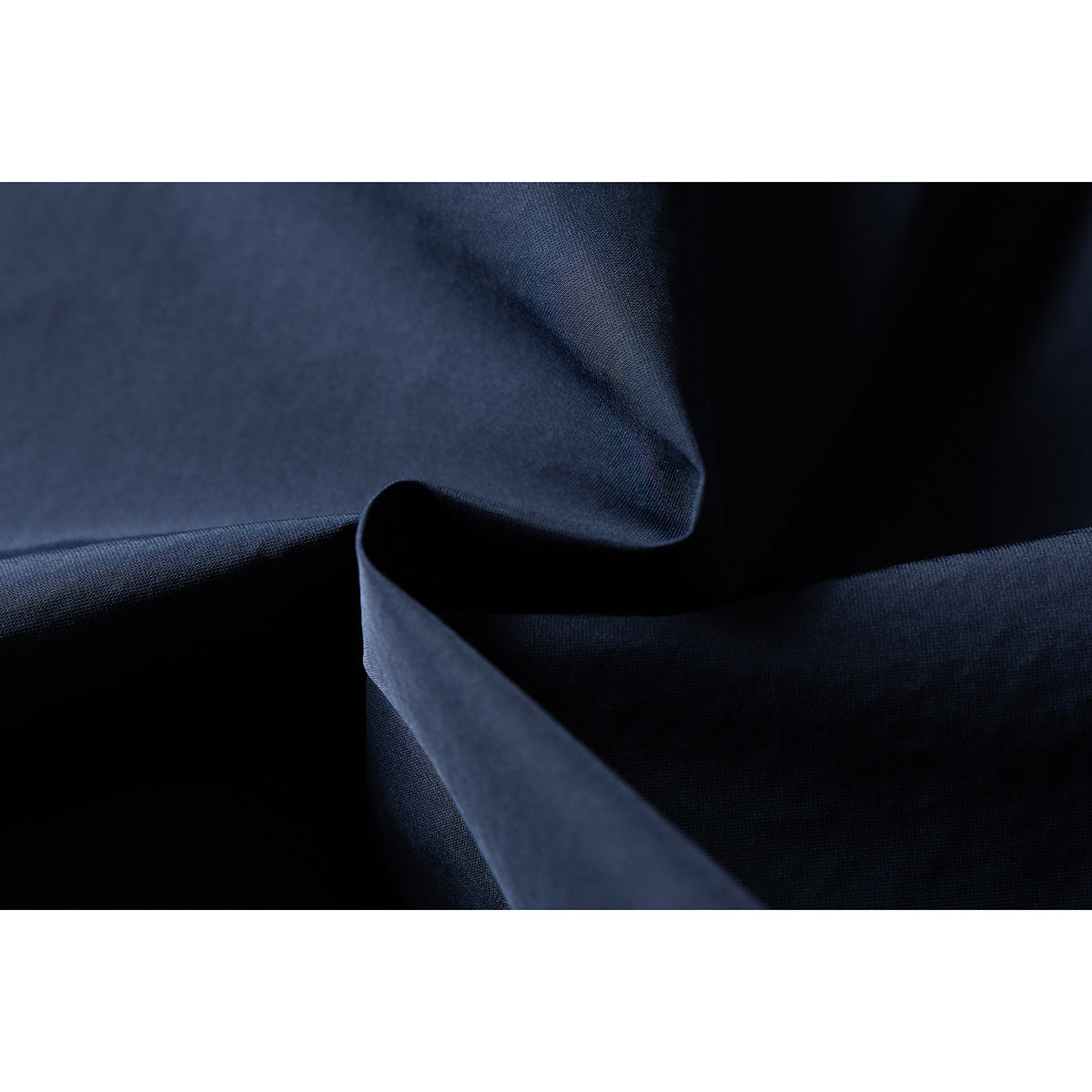 Macro view of dark navy jacket fabric folded to show its surface and texture.