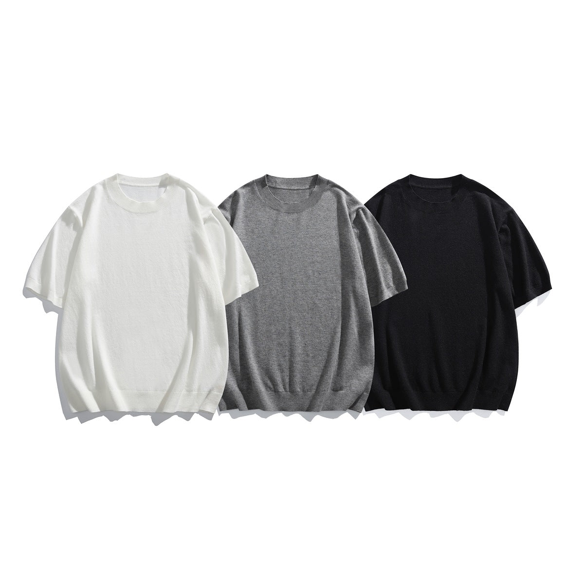 Three plain short-sleeve crew-neck knit sweaters shown from the front in white, gray, and black.