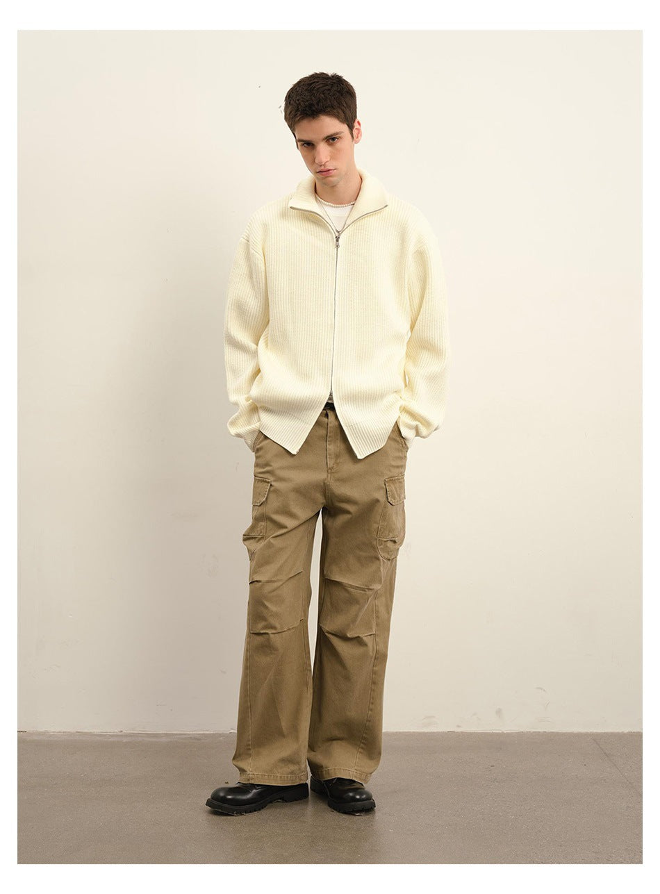 Full-length view of a model wearing an ivory ribbed zip cardigan and tan cargo trousers.