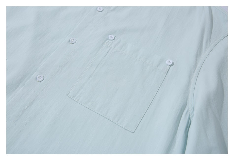 Close-up of a pale mint shirt showing its chest pocket and white buttons.