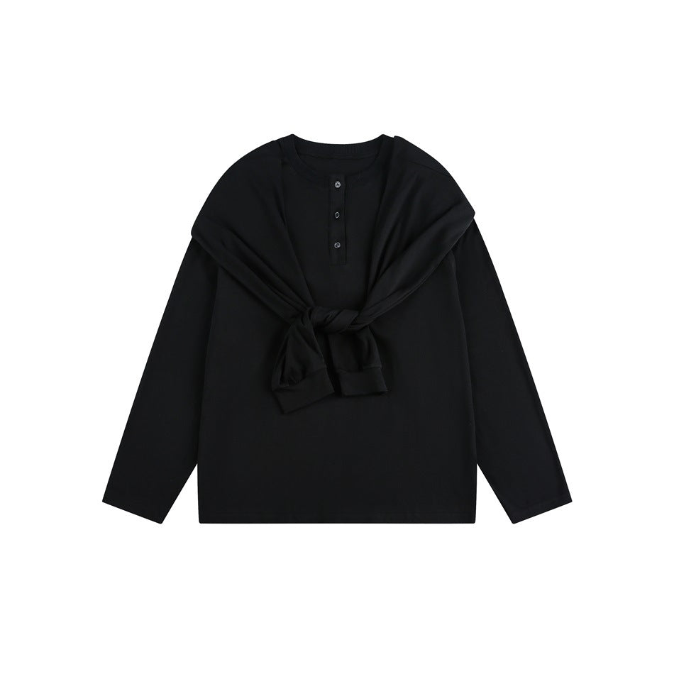 Black long-sleeve henley top with three buttons, styled with a black garment draped and tied across the chest.