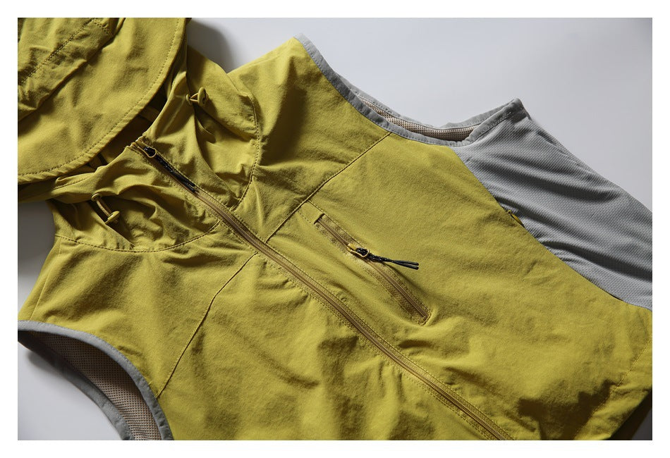 Close view of the mustard vest front showing its zipper, zip pocket, and gray mesh side panels.