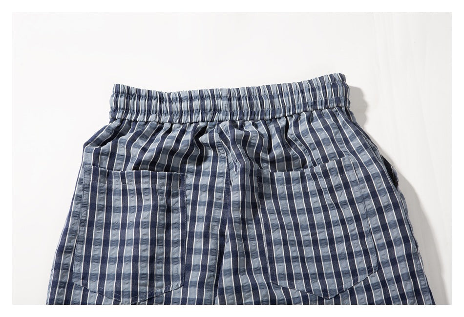 Cropped flat-lay view of blue-gray vertically striped shorts with an elastic waist and front pockets.