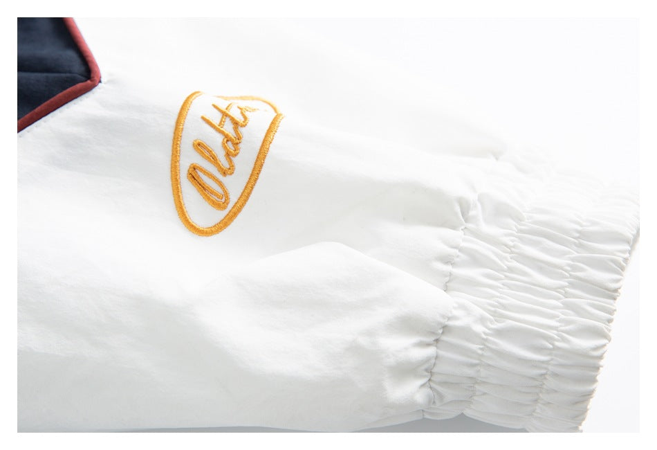 Close-up of a white sleeve with a gathered elastic cuff and gold embroidered script.