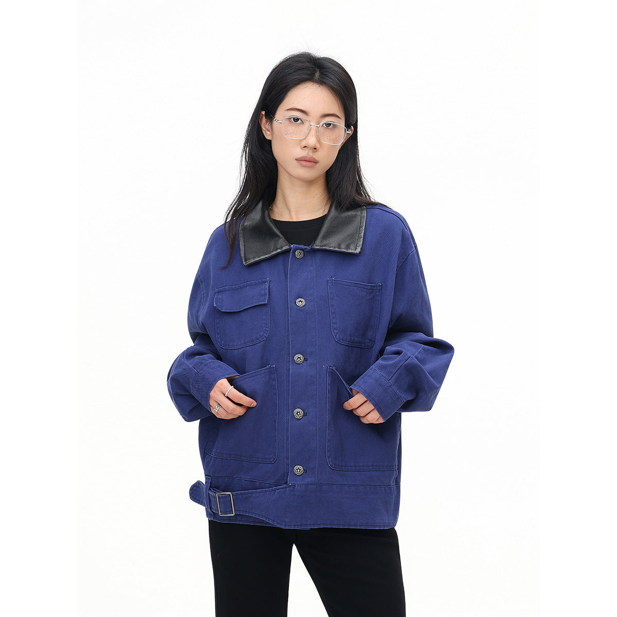 Model wearing a cobalt-blue oversized jacket with a black collar, star buttons, four pockets and an adjustable hem belt.